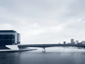 Bridge connecting a modern glass office building to a distant city skyline over calm misty water, symbolizing remote operations.
