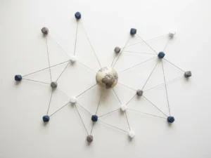 Geometric network nodes connected by thin lines on a white desk, with a small globe at the center suggesting global collaboration.