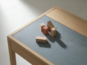 Five small wooden blocks clustered on an oak desk, one slightly apart casting a soft shadow in warm natural light.