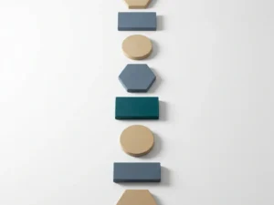 Geometrische stapstenen in leisteenblauw en zandtinten met één diepgroene steen, oplopend pad op wit oppervlak, minimalistisch bovenaanzicht.