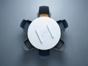 Bovenaanzicht van ronde vergadertafel met vijf minimalistische stoelen, opengerold architectuurplan in het midden, navy en grijstinten.